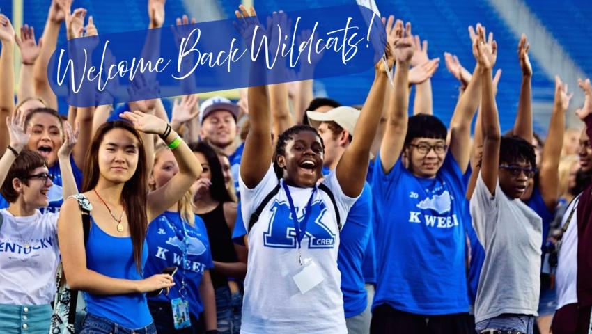 Students in a crowd wearing blue UK shirts raising both hands joyfully. Welcome Back Wildcats!
